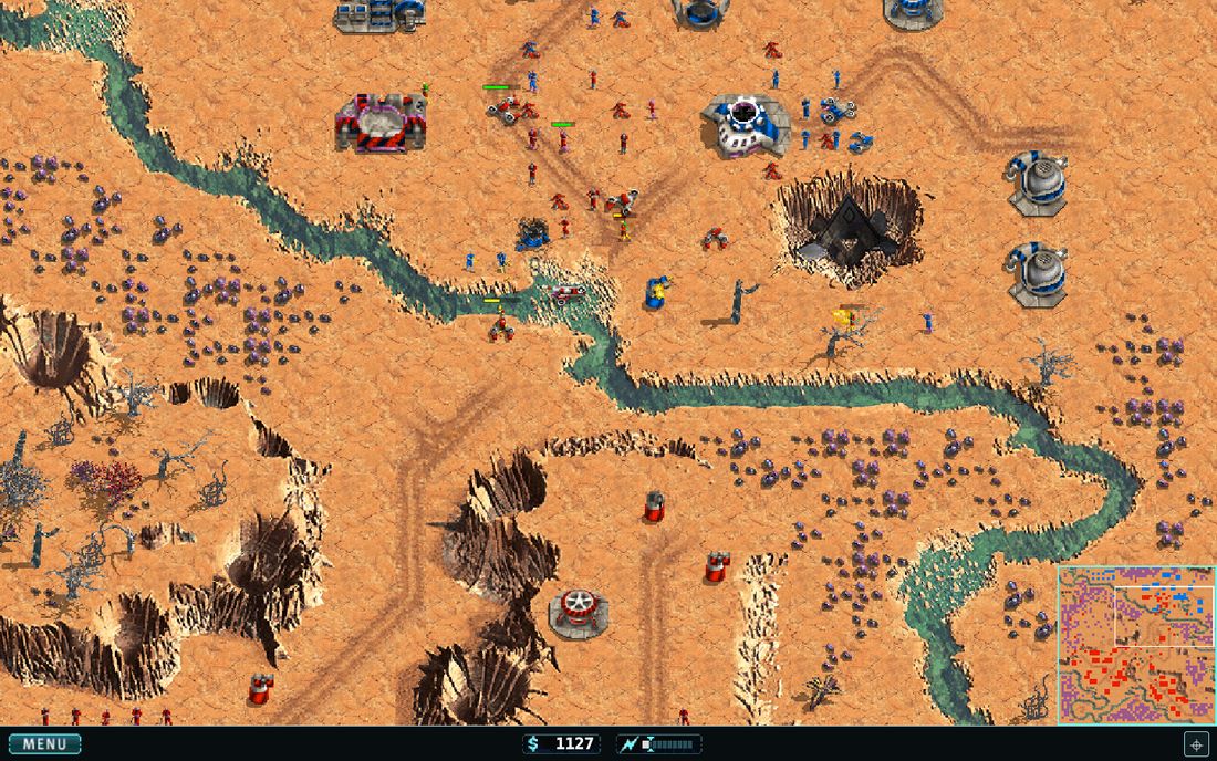 A battle in progress: blue and red forces engaged across an orange desert map, with the heads-up display and minimap.